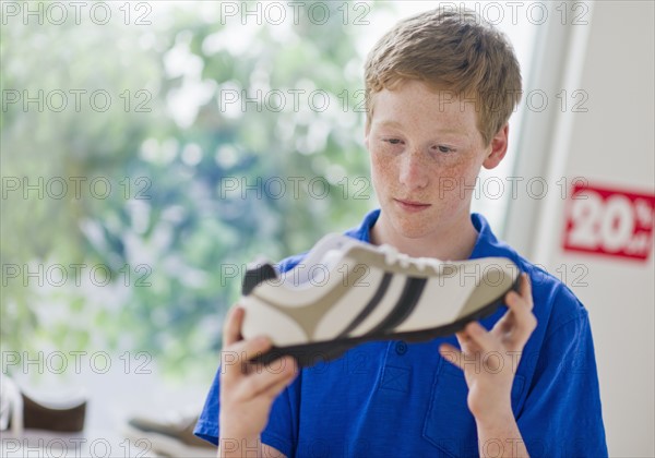 Boy (16-17) looking at shoe in shoe store.