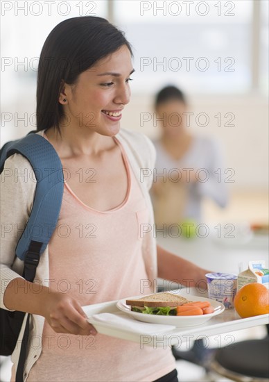 Female student carrying tray in cafeteria.