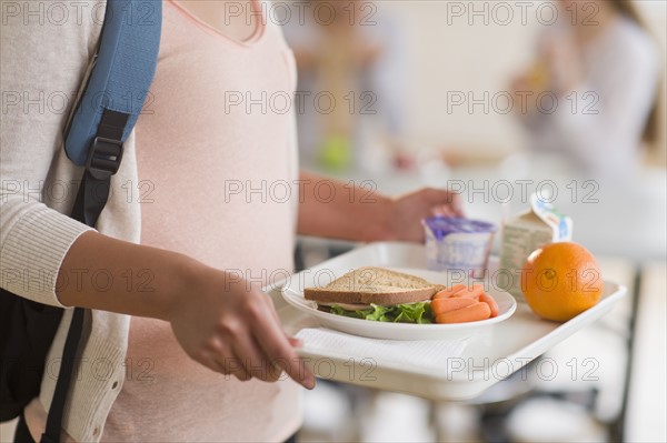 Female student carrying tray in cafeteria.