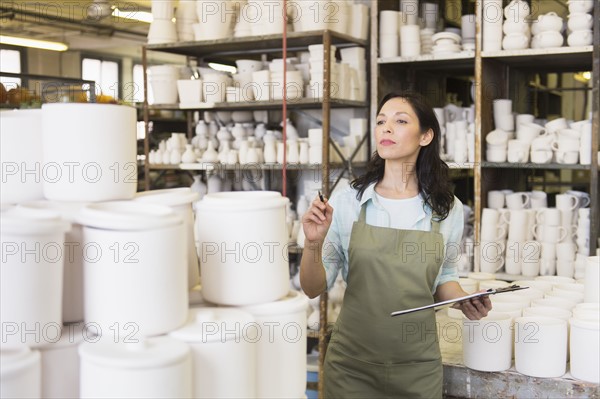 Woman with checklist in pottery warehouse.