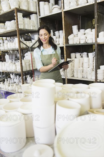 Woman with checklist in pottery warehouse.