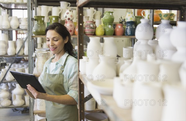 Woman with digital tablet in pottery warehouse.