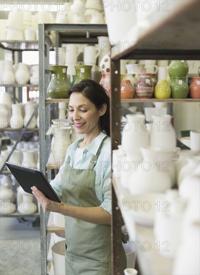 Woman with digital tablet in pottery warehouse.