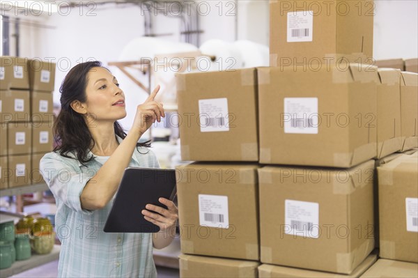 Woman counting boxes in warehouse.