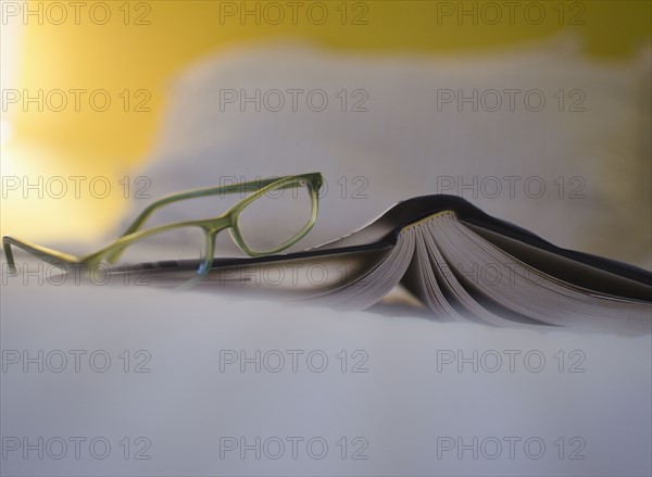 Book and eyeglasses on bed. 
Photo : Jamie Grill