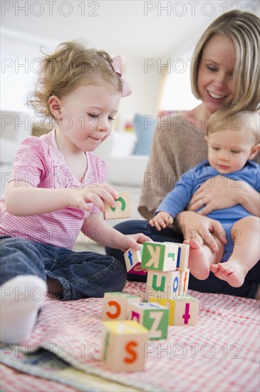 Mother playing with children (2-3, 6-11 months) at home. 
Photo : Jamie Grill