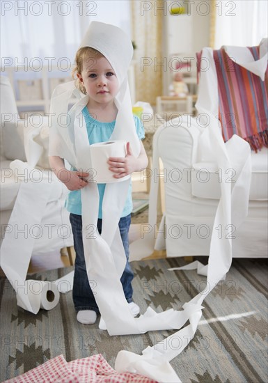 Girl (2-3) wrapped with toilet paper standing in living room. 
Photo : Jamie Grill