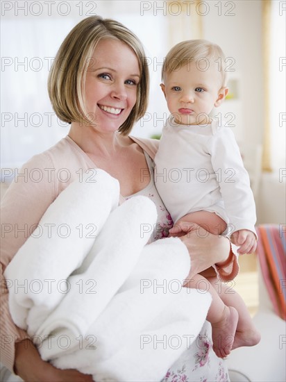 Mother holding son (6-11 months) and laundry. 
Photo : Jamie Grill