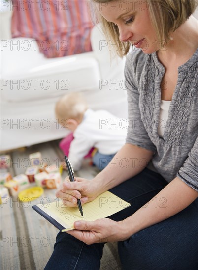 Mother doing notes, son (6-11 months) playing in background. 
Photo : Jamie Grill