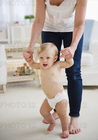 Baby boy (6-11 months) walking with mother. 
Photo : Jamie Grill