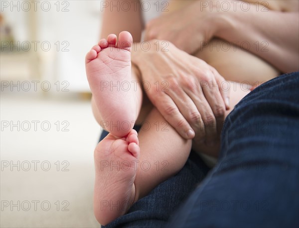 Mother holding son (6-11 months), close-up of baby feet. 
Photo: Jamie Grill