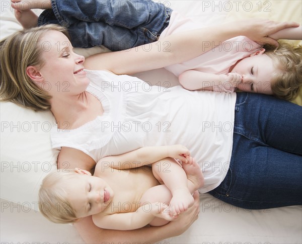 Mother and children (6-11 moths, 2-3) lying in bed. 
Photo: Jamie Grill