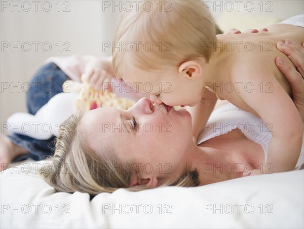 Mother kissing son (6-11 moths), daughter (2-3) in background . 
Photo : Jamie Grill