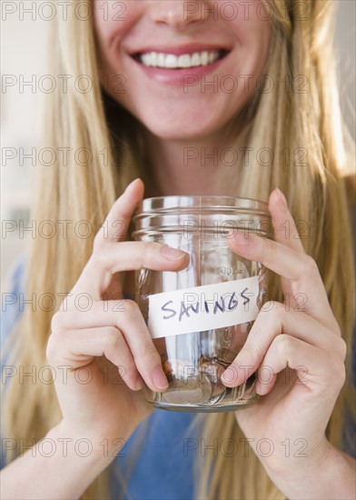 Woman holding jar with savings.
Photo : Jamie Grill