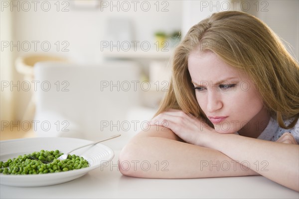 Woman leaning on table looking on green peas. 
Photo : Jamie Grill
