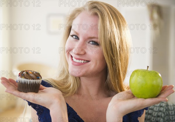 Woman holding apple and cupcake. 
Photo : Jamie Grill