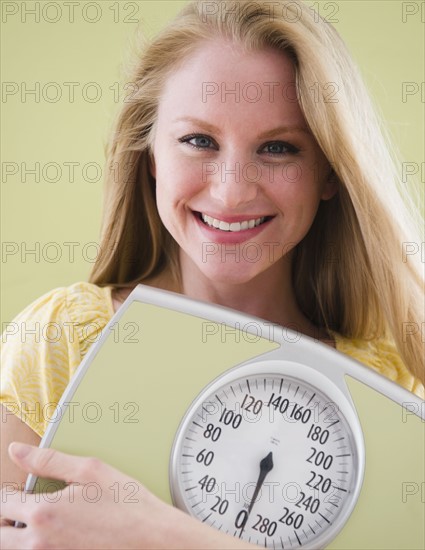 Woman holding bathroom scale. 
Photo : Jamie Grill