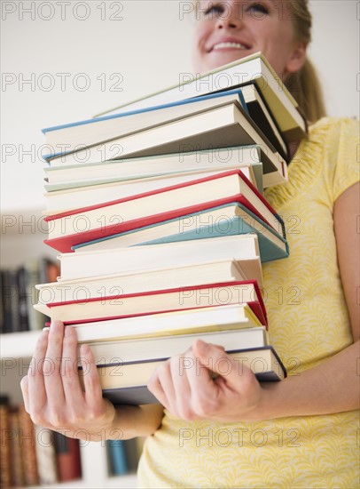 Woman carrying stack of books. 
Photo : Jamie Grill