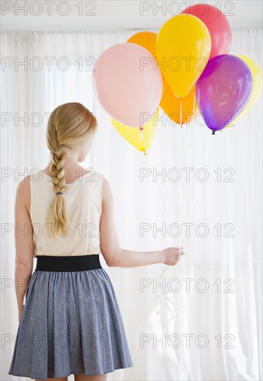 Woman holding bunch of colorful balloons. 
Photo : Jamie Grill