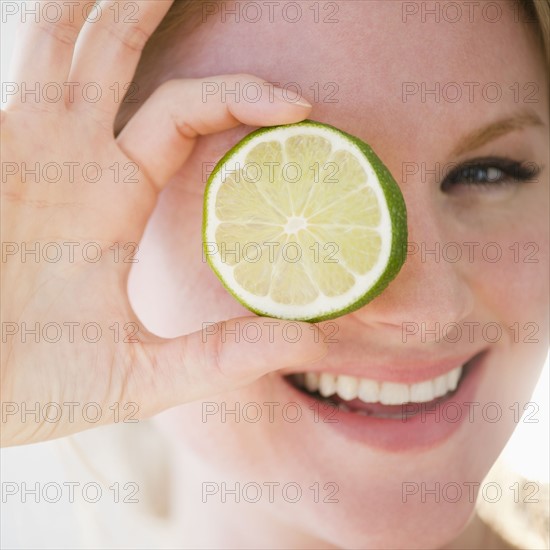 Portrait of woman holding slice of lime. 
Photo : Jamie Grill