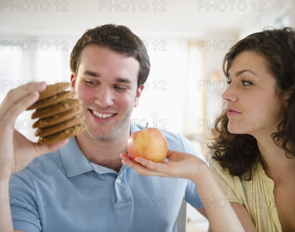 Couple holding cookies and apple. 
Photo : Jamie Grill