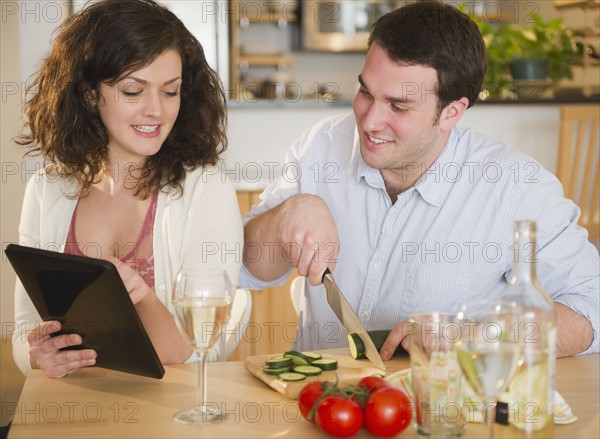 Couple preparing meal and using digital tablet. 
Photo : Jamie Grill