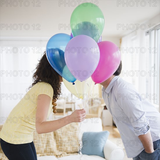 Couple kissing behind bunch of colorful balloons.
Photo : Jamie Grill