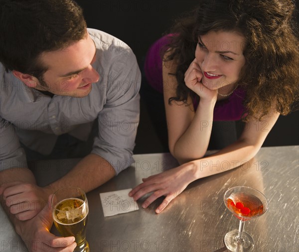 Flirting couple sitting at bar counter. 
Photo : Jamie Grill