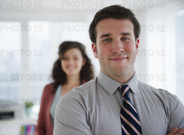 Portrait of business man, business woman in background. 
Photo : Jamie Grill