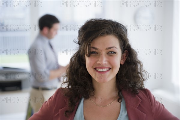 Portrait of business woman, business man in background. 
Photo : Jamie Grill