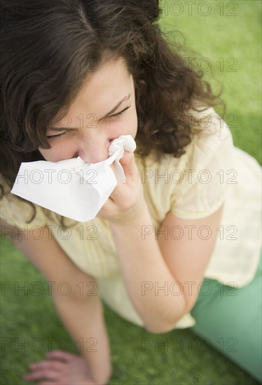 Woman blowing nose while sitting on lawn. 
Photo : Jamie Grill