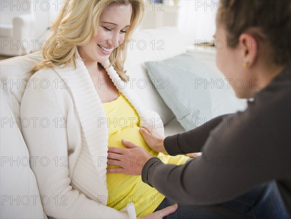 Woman touching belly of pregnant friend. 
Photo : Jamie Grill