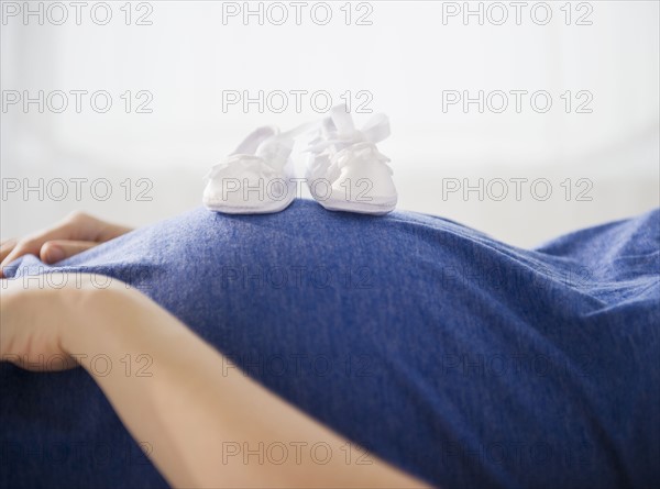 Pregnant woman with baby boots on belly. 
Photo : Jamie Grill