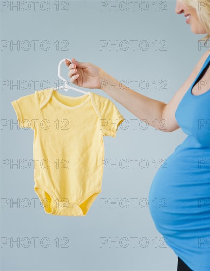 Pregnant woman holding onesie. 
Photo : Jamie Grill