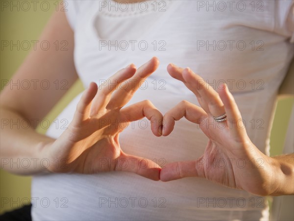 Pregnant woman making heart shape with hands. 
Photo: Jamie Grill