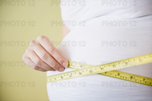 Pregnant woman measuring belly with tape measure.
Photo : Jamie Grill