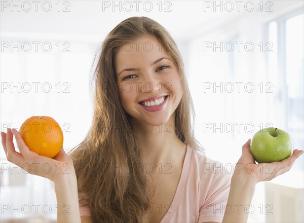 Woman holding orange and apple. 
Photo : Jamie Grill
