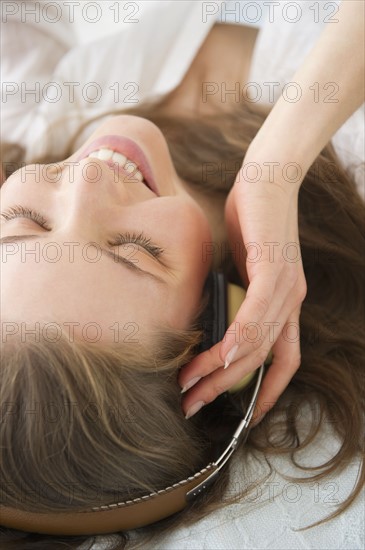 Woman lying on bed and listening to the music. 
Photo : Jamie Grill