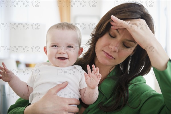 Tired mother holding baby daughter (6-11 months). 
Photo : Jamie Grill