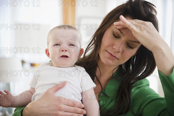 Tired mother holding baby daughter (6-11 months). 
Photo: Jamie Grill