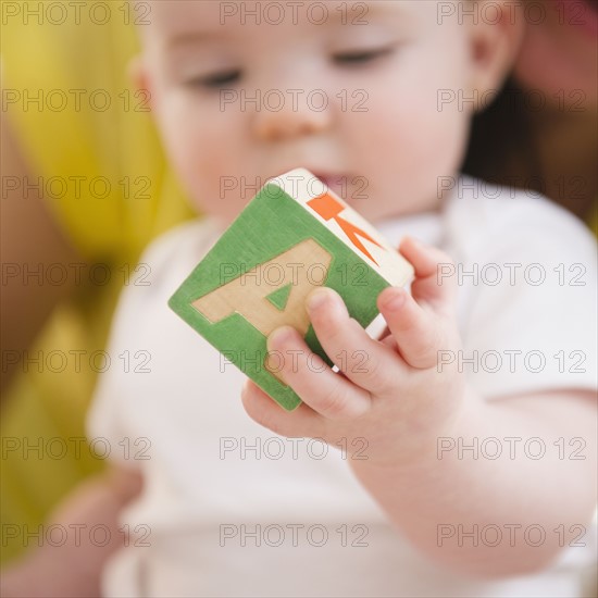 Baby girl (6-11 months) holding block. 
Photo: Jamie Grill