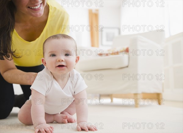 Mother and baby daughter (6-11 months) crawling on carpet. 
Photo : Jamie Grill