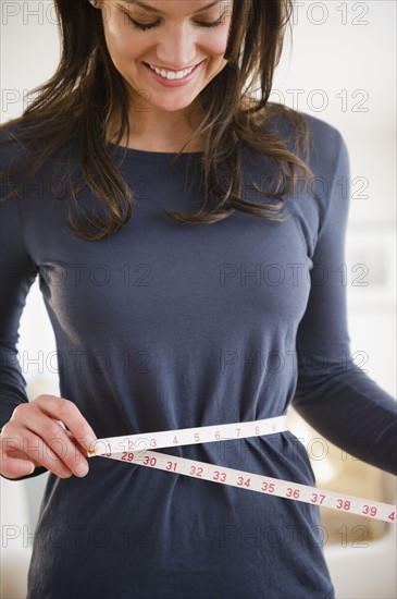 Woman measuring herself with measuring tape. 
Photo : Jamie Grill