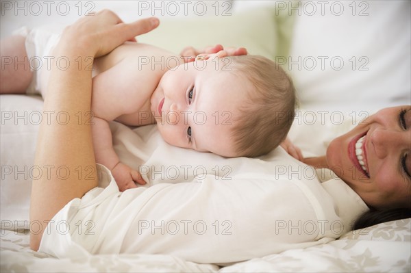 Mother with baby daughter (6-11 months) lying on bed. 
Photo : Jamie Grill