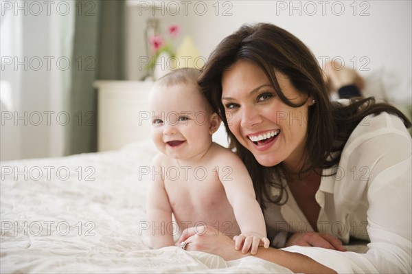 Mother with baby daughter (6-11 months) lying on bed. 
Photo : Jamie Grill