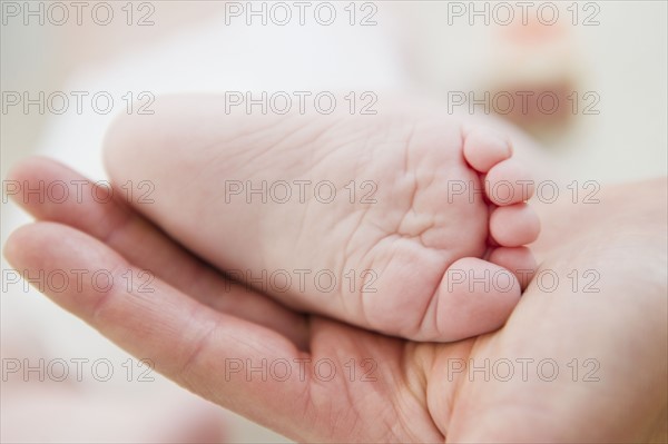 Close up of mother's hand holding baby daughter's (6-11 months) foot. 
Photo: Jamie Grill