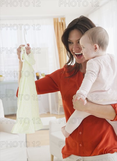 Mother with baby daughter (6-11 months) holding dress. 
Photo: Jamie Grill