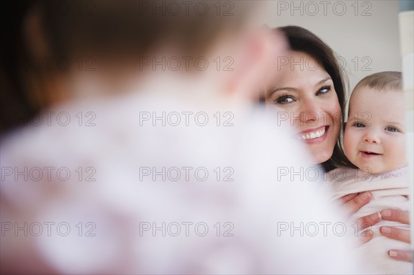 Mother with baby daughter (6-11 months) reflecting in mirror. 
Photo: Jamie Grill