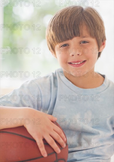 Portrait of smiling boy (10-11 years) with basketball ball. 
Photo: Daniel Grill