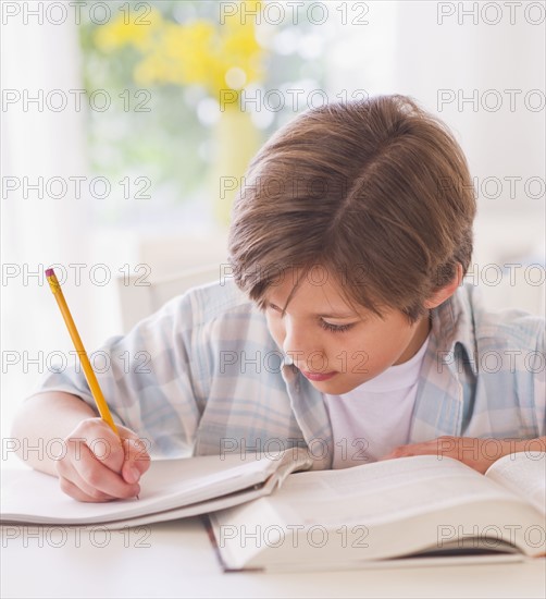 Boy (10-11 years) doing homework at table . 
Photo : Daniel Grill